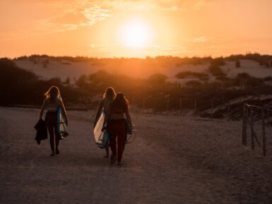 2 women walking on dirt road during sunset
